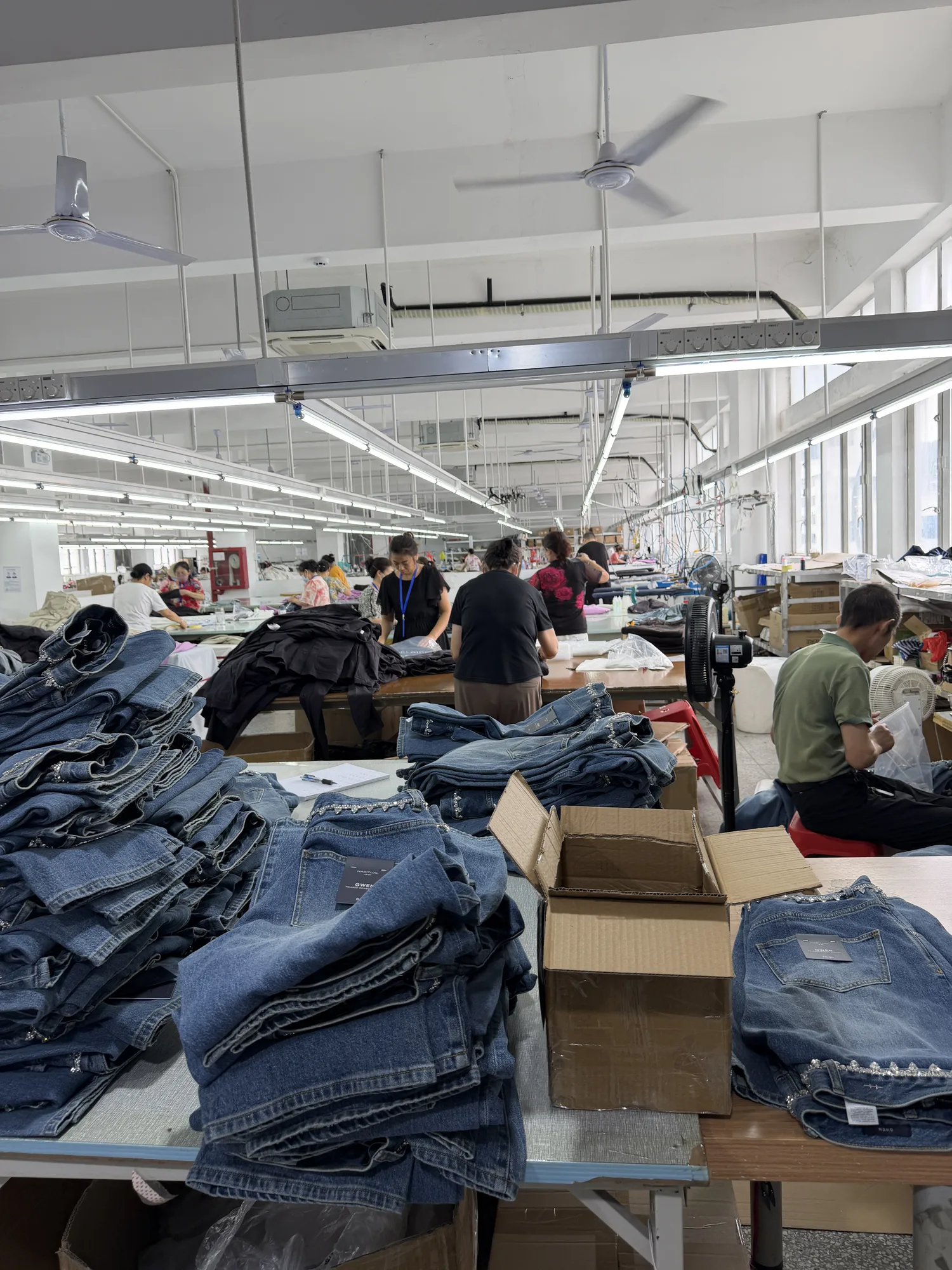 Finished denim garments stacked for inspection at XBL Clothing